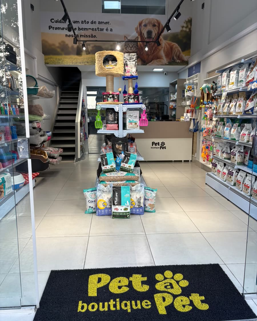 Interior da Pet a Pet: corredor com prateleiras de ração e acessórios, e o tapete com a logo na entrada